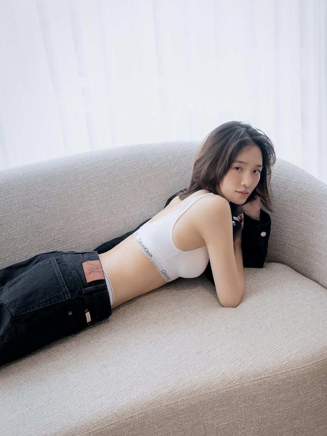 Photo shared by 박규영 on October 16, 2025 tagging @calvinklein. May be an image of one or more people, hair, sleepwear, chemise, chaise lounge, bra, futon and text.