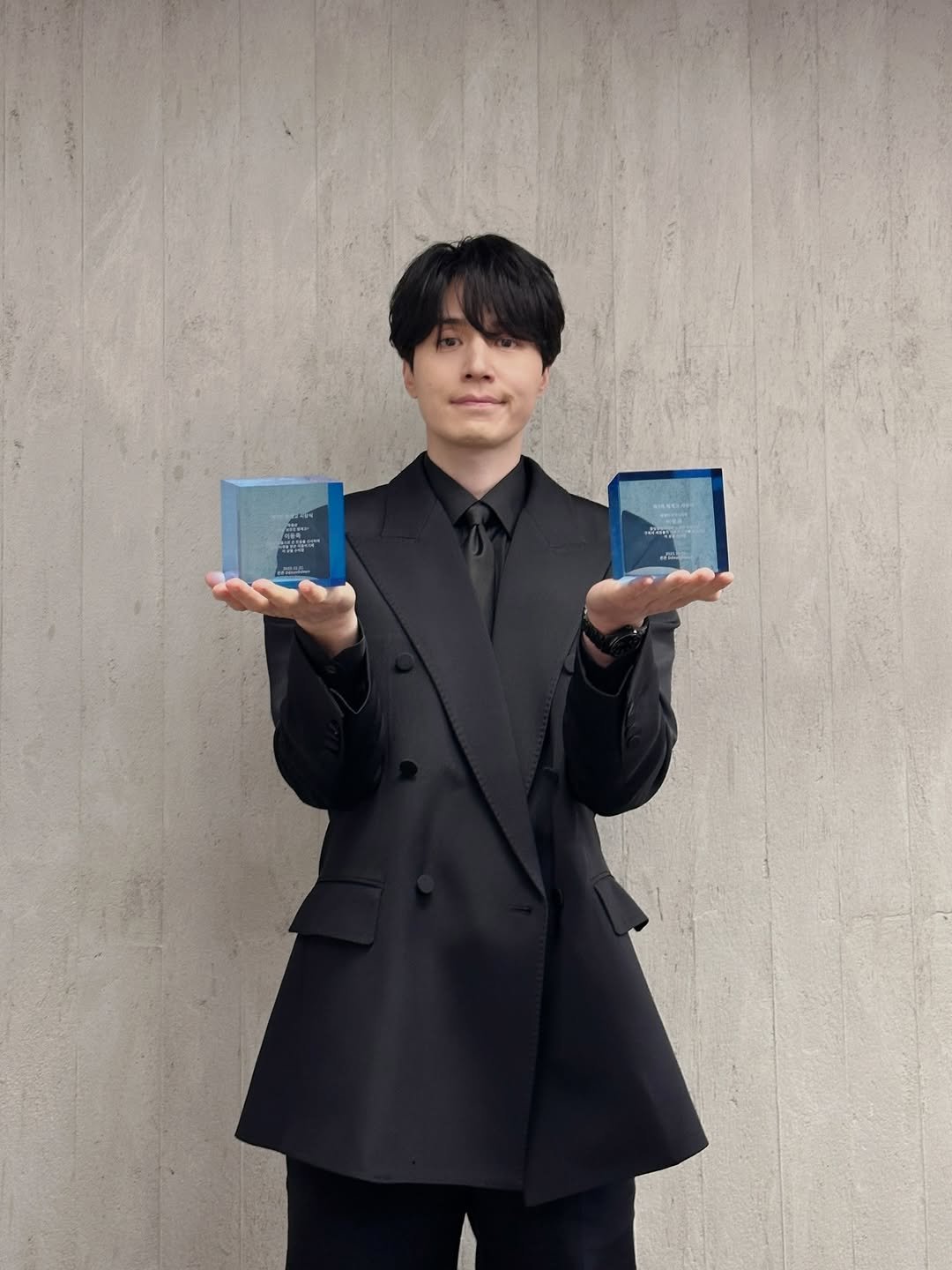 Photo by 이동욱 (Official_Instagram) on December 20, 2025. May be an image of duffle coat, phone, overcoat, blazer, suit and text.