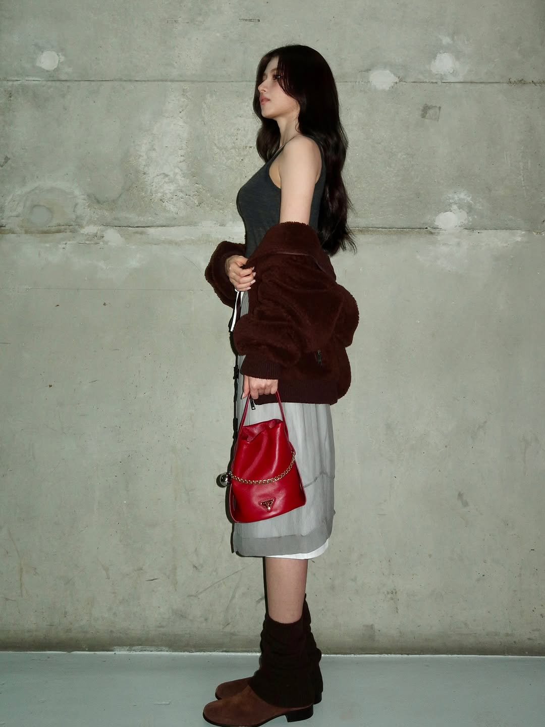 Photo shared by 사나 𝚂𝚊𝚗𝚊 on December 29, 2025 tagging @prada. May be an image of duffle coat, overcoat, purse, miniskirt and text.